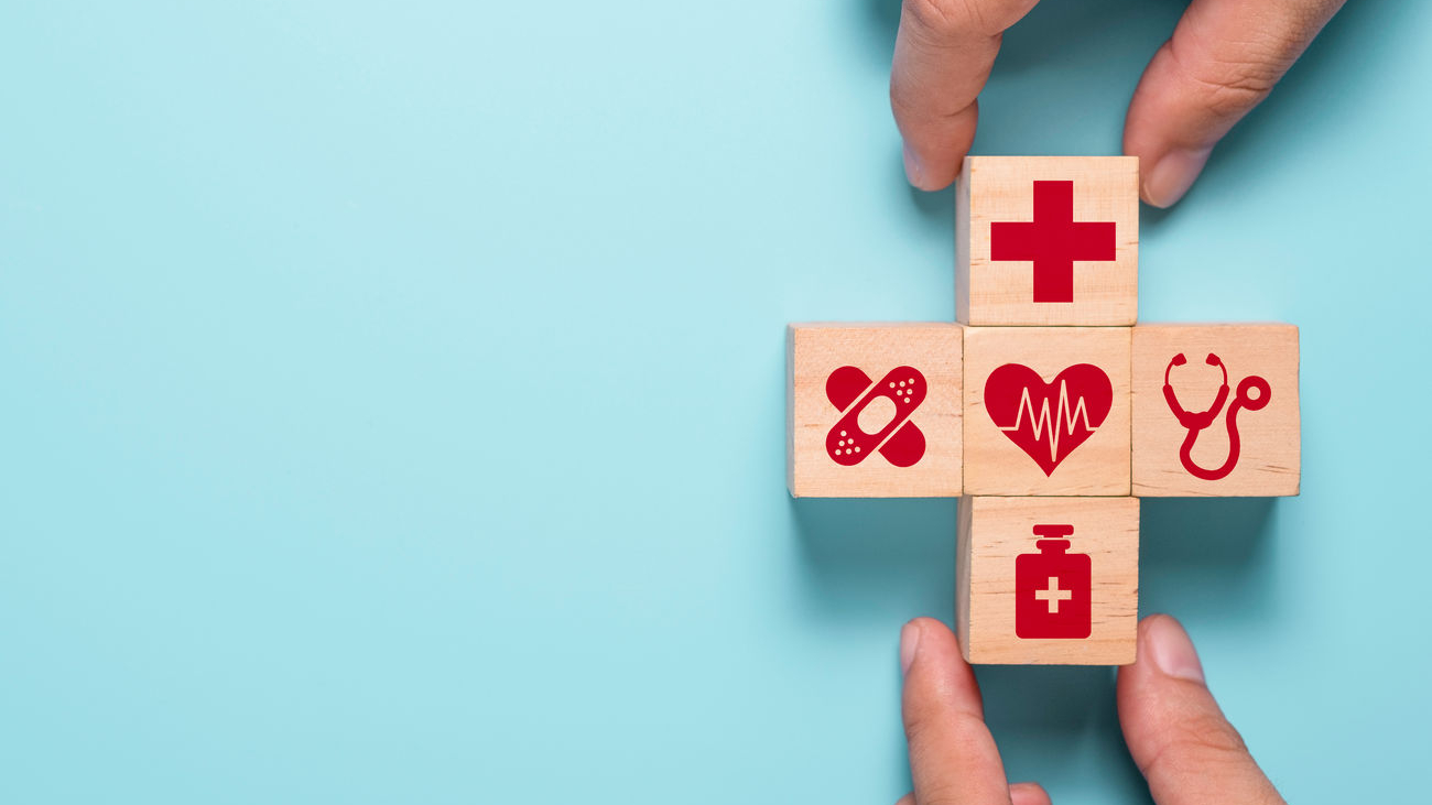hand-putting-wooden-cubes-of-healthcare-medicine-and-hospital-icon-on-blue-table-health-care-insurance-business-and-investment